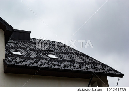House with new brown metal tile roof and rain gutter. Metallic Guttering System, Guttering and Drainage Pipe Exterior House with new brown metal tile roof and rain gutter. Metallic Guttering System, Guttering and Drainage Pipe Exterior 101261789