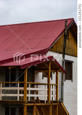 House with new brown metal tile roof and rain gutter. Metallic Guttering System, Guttering and Drainage Pipe Exterior 101261791