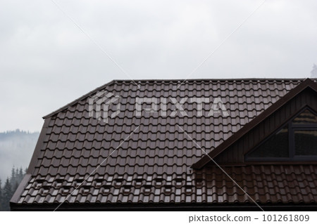 House with new brown metal tile roof and rain gutter. Metallic Guttering System, Guttering and Drainage Pipe Exterior 101261809