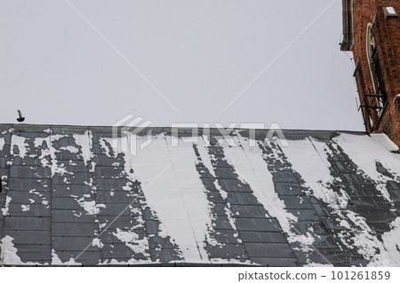 Snow on metal tiles roof of a european house with window 101261859