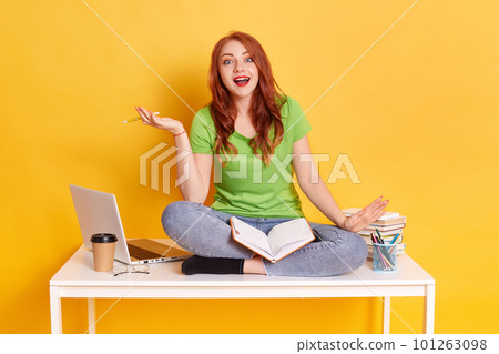 Portrait of attractive focused knowledgeable girl reading book, finding solution isolated yellow color background, spreading hand with pen aside, looks happy and excited, keeps mouth opened. Portrait of attractive focused knowledgeable girl reading book, finding solution isolated yellow color background, spreading hand with pen aside, looks happy and excited, keeps mouth opened. 101263098