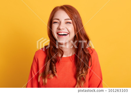 Young laughing woman against yellow background, looks happy, wearing orange sweater, expressing positive emotions, has red way hair, being in good mood. Young laughing woman against yellow background, looks happy, wearing orange sweater, expressing positive emotions, has red way hair, being in good mood. 101263103