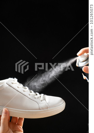 Applying a water-repellent hydrophobic spray to white women's sneakers. Protection of shoes from moisture, dirt and unpleasant odor. Applying a water-repellent hydrophobic spray to white women's sneakers. Protection of shoes from moisture, dirt and unpleasant odor. 101265073