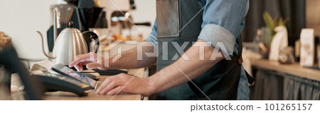 Close up of male barista working in cafeteria and takes order from clients Close up of male barista working in cafeteria and takes order from clients 101265157