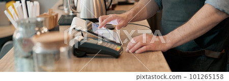 Close up of male barista working in cafeteria and writing order of clients Close up of male barista working in cafeteria and writing order of clients 101265158
