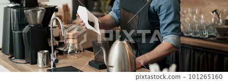 Barista pours coffee beans into the coffee machine tank for grinding at coffeeshop 101265160