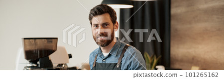Barista with stylish beard smiling while behind a counter in the coffeeshop Barista with stylish beard smiling while behind a counter in the coffeeshop 101265162