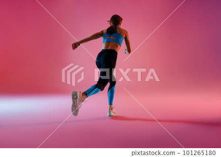 Sporty determined woman running during cardio workout over studio background 101265180
