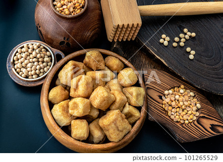 Brown fried tofu puffs or Deep Fried Tofu in wooden bowl and grains (soybeans) with dark background. Brown fried tofu puffs or Deep Fried Tofu in wooden bowl and grains (soybeans) with dark background. 101265529