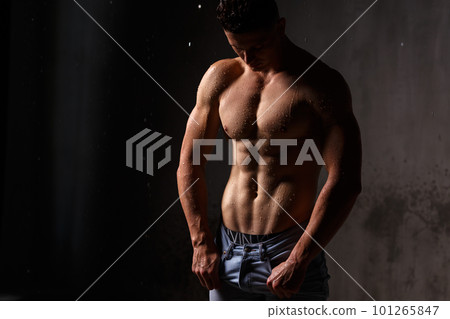 Athlete bodybuilder trains in the studio in the rain. 101265847