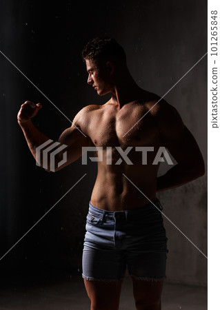 Athlete bodybuilder trains in the studio in the rain. 101265848