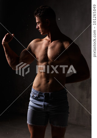 Athlete bodybuilder trains in the studio in the rain. 101265849