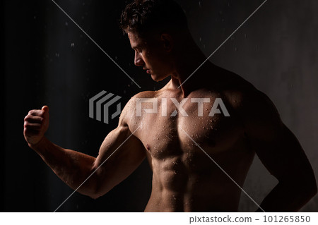 Athlete bodybuilder trains in the studio in the rain. 101265850