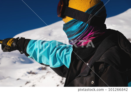Side view of a tourist pointing with his hand in the right direction. Young man looking for direction in snowy mountains, portrait 101266842