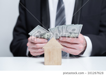 Two wooden houses and us money dollars in businesman hands. Byuing property,  insurance concept 101267628