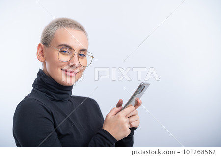 Young caucasian woman with short hair uses a smartphone on a white background. Young caucasian woman with short hair uses a smartphone on a white background. 101268562