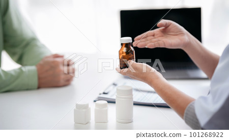 Female doctor showing bottle of pills to explaining medicine use 101268922