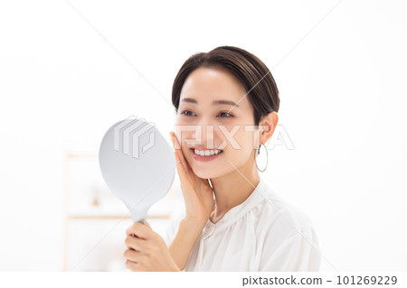 Stock photo of a woman checking her makeup with a hand mirror 101269229