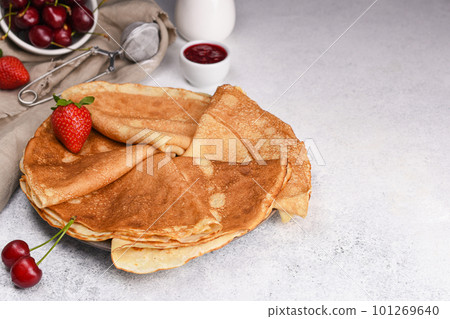 Thin pancakes for breakfast. Folded crepe with berries and jam on light background with copy space. Sweet cherry and strawberry nest to plate with pancakes. Thin pancakes for breakfast. Folded crepe with berries and jam on light background with copy space. Sweet cherry and strawberry nest to plate with pancakes. 101269640