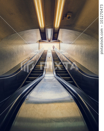 Lone man climbing out on a subway escalator. Symmetrical underground moving staircase 101270473