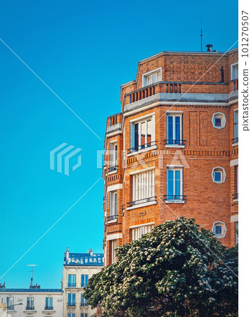 Beautiful orange brick building with a blooming tree at the bottom under a clear blue sky background in Asnieres-sur-seine a suburb of Paris, France Beautiful orange brick building with a blooming tree at the bottom under a clear blue sky background in Asnieres-sur-seine a suburb of Paris, France 101270507