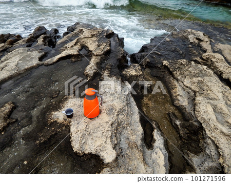 Orange thermos on the shore. 101271596