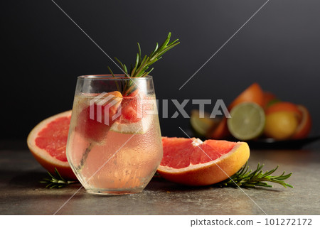 Cocktail gin tonic with ice, rosemary, and grapefruit on a stone table. 101272172