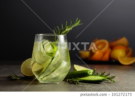 Cocktail gin tonic with ice, rosemary, lime, and cucumber on a stone table. 101272173