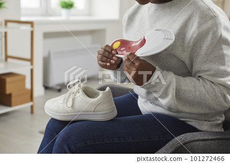 Young African American woman holding an orthotic arch support insole for her shoes Young African American woman holding an orthotic arch support insole for her shoes 101272466