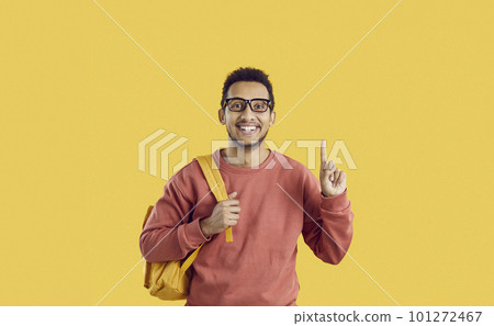 Happy college student struck by a good idea is pointing his finger up and smiling Happy college student struck by a good idea is pointing his finger up and smiling 101272467