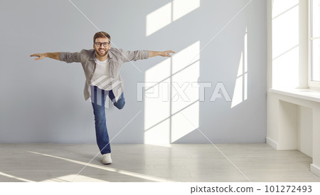 Happy young man in casual clothes standing on one leg while doing fitness exercises 101272493