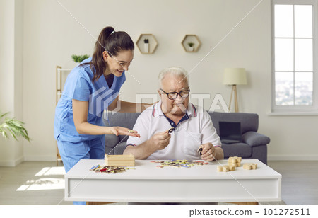 Nurse in retirement home helping senior man with Alzheimer's disease with puzzles 101272511