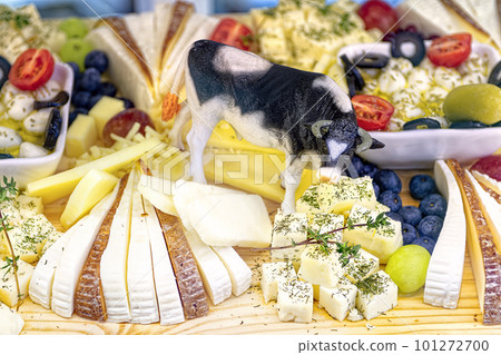 Various sliced cheeses on wooden table. Figurine of cow in the middle of slices of cheese. 101272700