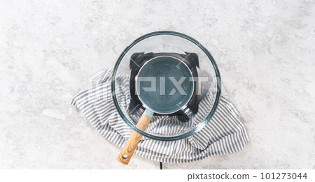 Flat lay. Melting chocolate chips and other ingredients in a glass mixing bowl over boiling water to prepare candy corn fudge. Flat lay. Melting chocolate chips and other ingredients in a glass mixing bowl over boiling water to prepare candy corn fudge. 101273044