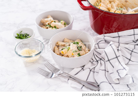 Chicken alfredo pasta with green peas and rigatoni pasta in a small bowl. 101273115