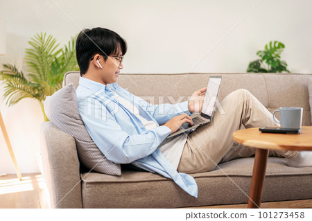 Businessman in casual is lying on comfortable sofa and wearing h 101273458