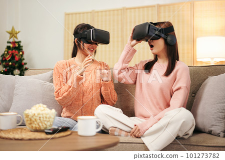 Young woman lesbian couple wearing sweater and VR goggles to pla Young woman lesbian couple wearing sweater and VR goggles to pla 101273782