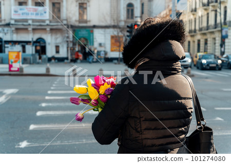 Woman holding tulips on a street in Bucharest, Romania 101274080