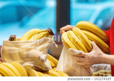 Woman picking bananas in a reusable bag. Ecology, Earth Day thematics 101274107
