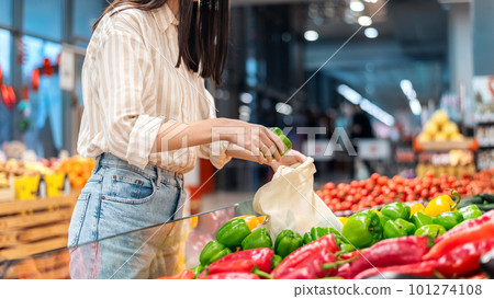 Woman picking bell peppers in a reusable bag. Ecology, Earth Day thematics 101274108