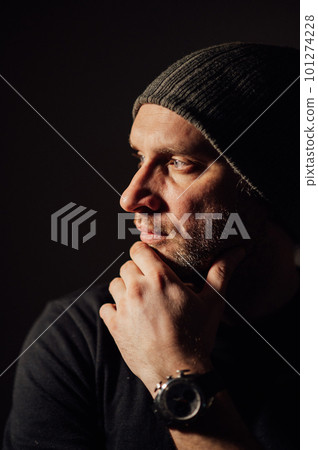 Serious dramatic man looking away while standing against black studio background Serious dramatic man looking away while standing against black studio background 101274228