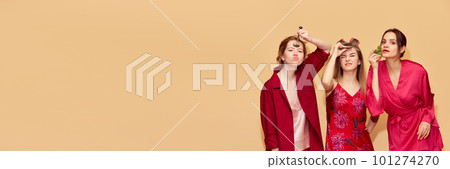 Funny faces. Pretty young girls in pajamas and robes taking care after skin with massage tools against studio background 101274270