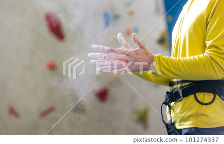 Athletic young man using magnesium for dry hands, dust flies from talcum powder, white chalk powder, indoor wall climbing concept Athletic young man using magnesium for dry hands, dust flies from talcum powder, white chalk powder, indoor wall climbing concept 101274337