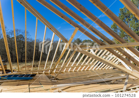 Under construction is timber truss framed building with rafters, roof beams wooden joists which will serve as framework for building 101274528