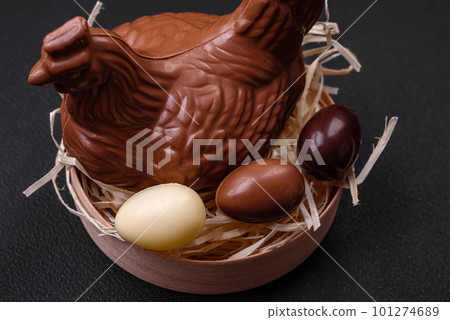 Chocolate Easter hen and eggs in a nest with straw 101274689