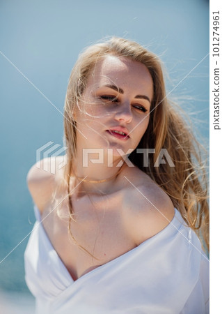 Portrait of a blond woman at the sea, a woman makes photos for memory from a trip to the sea to show to friends. Portrait of a blond woman at the sea, a woman makes photos for memory from a trip to the sea to show to friends. 101274961