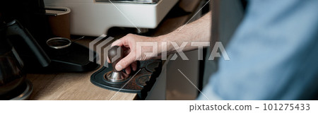 barista holding tamper standing behind a counter 101275433