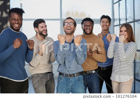 Group of happy managers rejoice at a successful deal by clenching their hands into fists and raising them up 101276104
