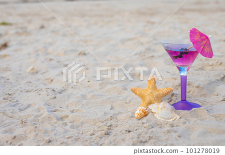 Glass of cocktail on sandy beach and starfish next to sea Glass of cocktail on sandy beach and starfish next to sea 101278019