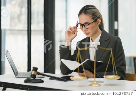 A businesswoman and lawyers are discussing contract papers with a brass scale on a desk in an office. The concepts of law, legal services, advice, justice, and real estate are being discussed. 101278737